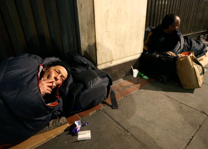 Two homeless men lie against a building near Victoria rail station