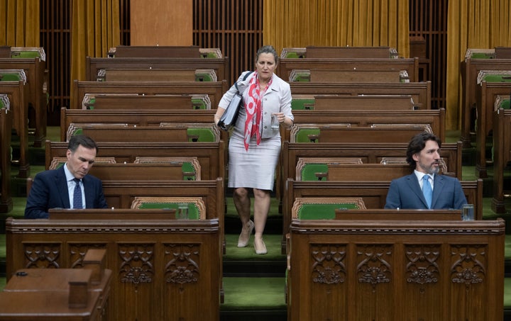 Deputy Prime Minister Chrystia Freeland looks for a seat as Bill Morneau and Prime Minister Justin Trudeau wait in the House of Commons on May 13, 2020.