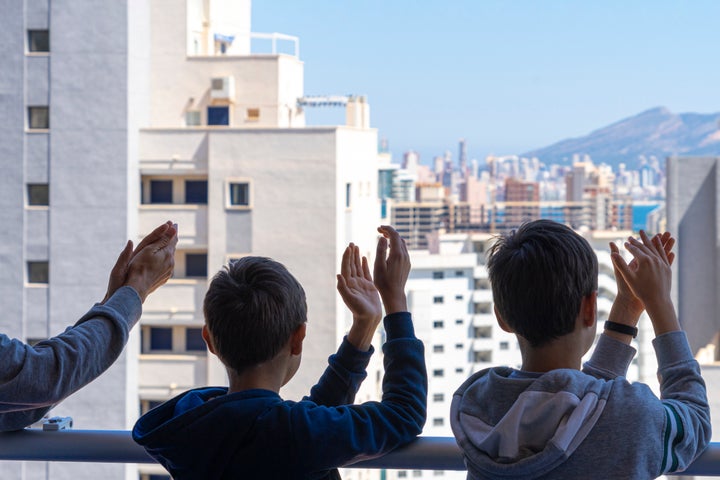 Niños aplauden a los sanitarios desde su balcón.