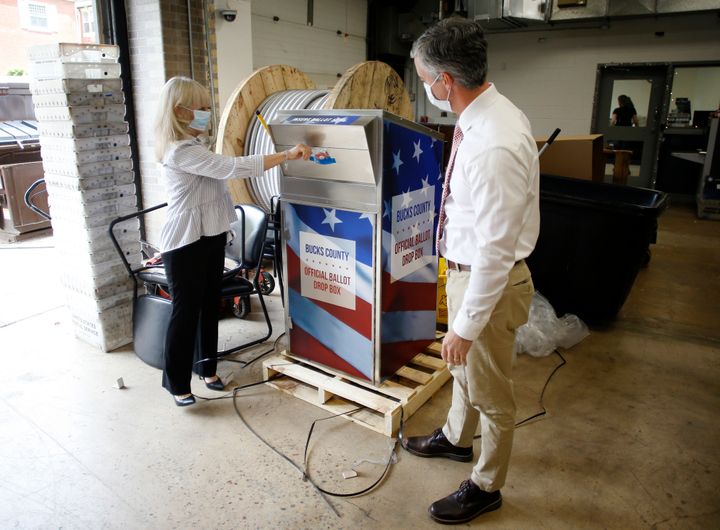 In this May 27, 2020, file photo, Bucks County commissioners Diane Ellis-Marseglia, left, and Robert Harvie unpack a new ballot drop box at the county's administration building prior to the primary election in Doylestown, Pa. (AP Photo/Matt Slocum, File)