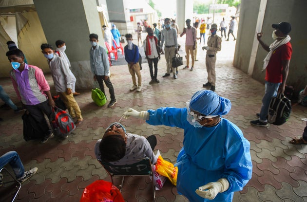 Migrant workers arriving from other states get rapid antigen tests for COVID-19 at Anand Vihar bus terminal...