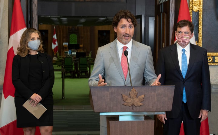 Deputy Prime Minister and Minister of Finance Chrystia Freeland and Minister of Intergovernmental Affairs Dominic LeBlanc look on as Prime Minister Justin Trudeau speaks during a news conference in the House of Commons foyer on Aug. 18, 2020. 