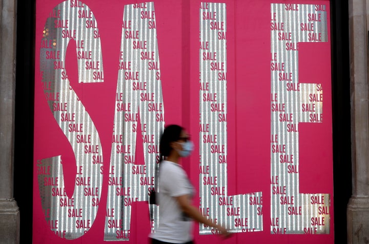 A pedestrian passes a sale sign in a shop window on Oxford Street in London, Thursday, Aug. 13, 2020. The British economy is on course to record the deepest coronavirus-related slump among the world's seven leading industrial economies after official figures showed it shrinking by a 20.4% in the second quarter of 2020 alone said The Office for National Statistics. (AP Photo/Kirsty Wigglesworth)