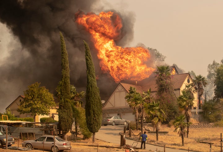 A man trying to save a home in Vacaville, California, on Wednesday watches futilely as it goes up in flames.