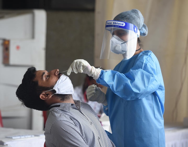 A health worker takes samples for Covid-19 rapid antigen tests at a testing facility at Anand Vihar Bus Terminal on August 17, 2020 in New Delhi.