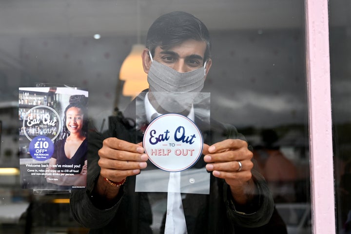 U.K. Chancellor of the Exchequer Rishi Sunak places an Eat Out to Help Out sticker in the window of a business. The government has spent millions of pounds on the program, which subsidizes the cost of restaurant meals.