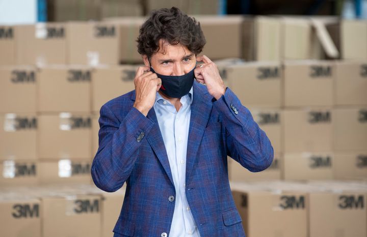 Prime Minister Justin Trudeau removes a cloth mask as he approaches the podium during an announcement at a factory in Brockville, Ont., on Aug. 21, 2020.