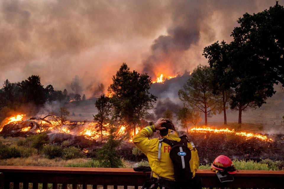 A firefighter rubs his head while watching the LNU Lightning Complex fires spread through the Berryessa Estates.