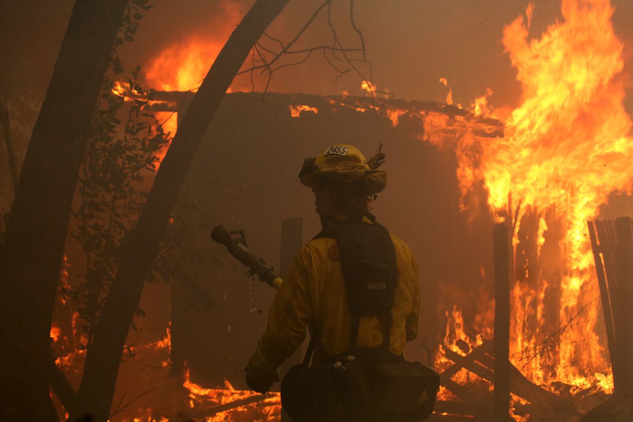 A firefighter uses a hose on a burning house in Bonny Doon, California. 