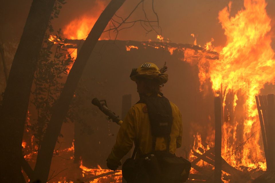 A firefighter uses a hose on a burning house in Bonny Doon, California. 