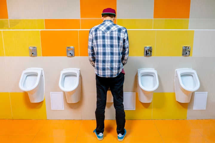 young man in the public toilet, standing next to the urinal in the trade center