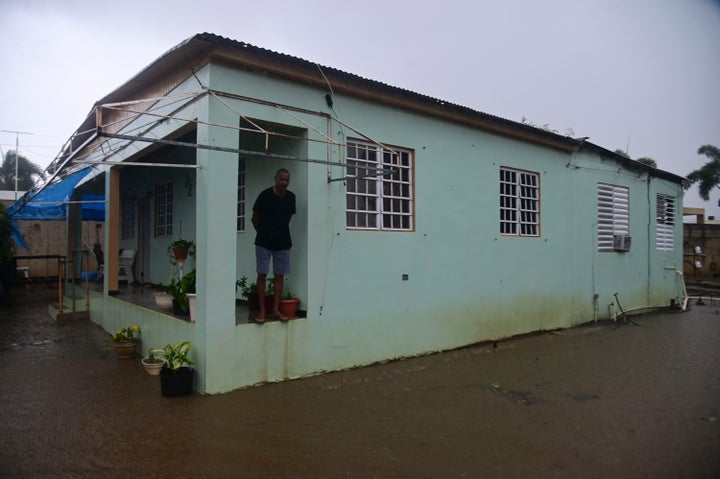 A resident stands on the porch of his home flooded by rains caused by Tropical Storm Laura in Salinas, Puerto Rico, Saturday, Aug. 22, 2020. (AP Photo/Carlos Giusti)