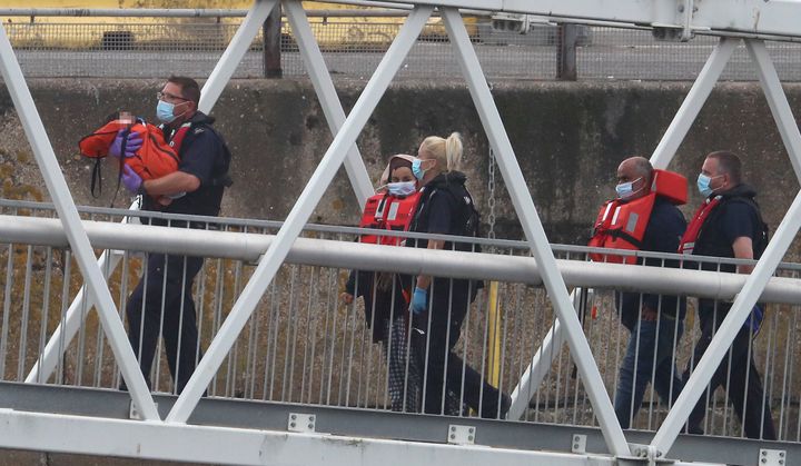 A Border Force officer carries a young child as a group of people thought to be migrants are brought into Dover, Kent, on a Border Force vessel