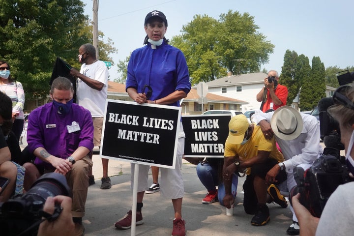 A small group of demonstrators pray while protesting Sunday evening's police shooting of a Black man in Kenosha, Wisconsin. J