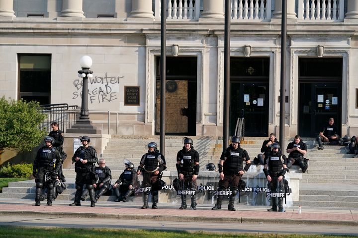 Police in riot gear stand outside the Kenosha County Court House on Monday following overnight protests over the shooting of a Black man by police.