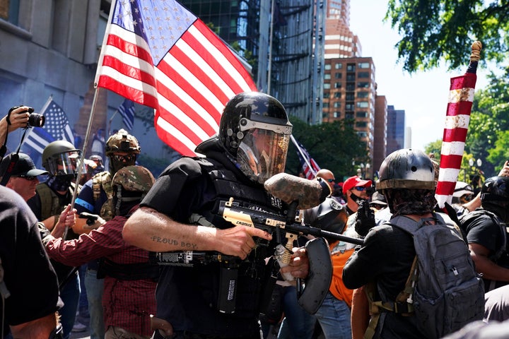 A member of the Proud Boys fires a paintball gun into a crowd of protesters against police brutality as the two sides clashed on Aug. 22 in Portland. For the second Saturday in a row, right-wing groups gathered in downtown Portland, sparking counterprotests and leading to violence.