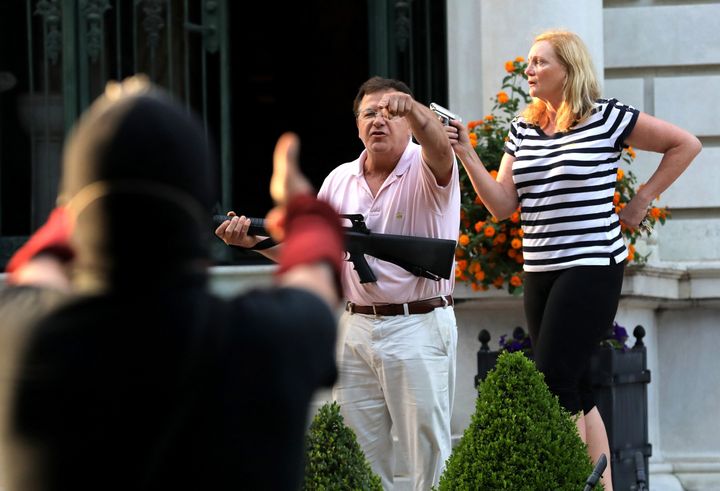 Armed homeowners Mark and Patricia McCloskey stand in front of their house as they confront protesters, June 28, 2020, in the Central West End of St. Louis.