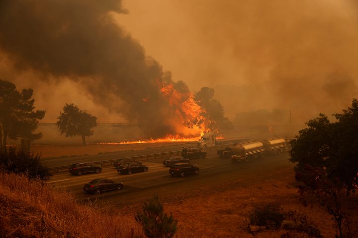 Vehicles drive along Interstate 80 as flames from the LNU Lightning Complex Fire rage on the outskirts of Vacaville, California.