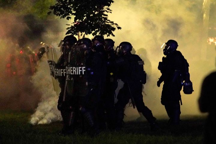 Police in riot gear clear a park during clashes with protesters outside the Kenosha County Courthouse late Tuesday.