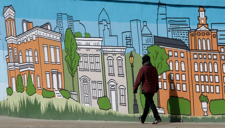 A pedestrian walks past a mural showing the skyline and several landmark buildings of Cincinnati. The city faces a housing shortage as well as a wave of pandemic-related evictions.