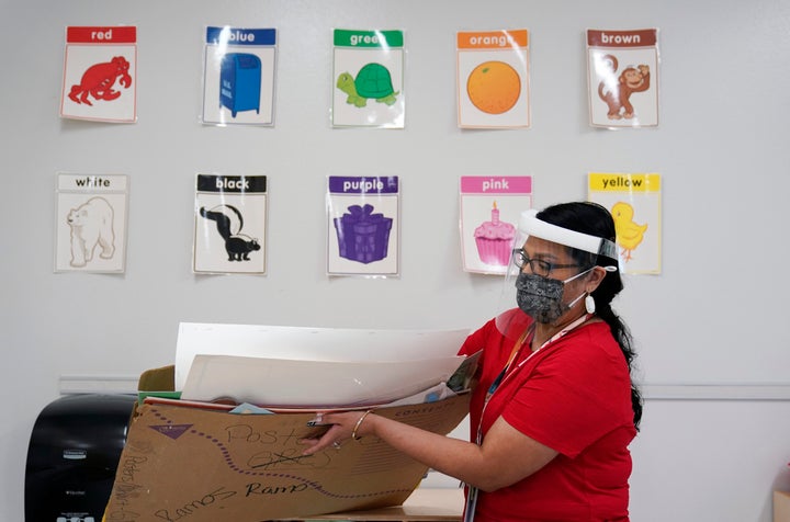 Wearing a face mask and shield to protect against the spread of COVID-19, kindergarten teacher Judith Ramos prepares her classroom this month in San Antonio. Southside will begin the year with remote teaching and has added hotspots to the school district to help students without access to the internet. (AP Photo/Eric Gay)