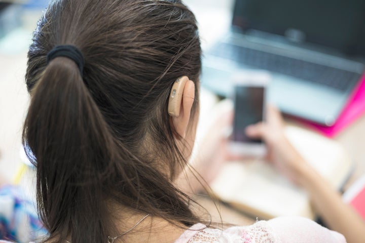 Girl with hearing aid studying and use mobile phone