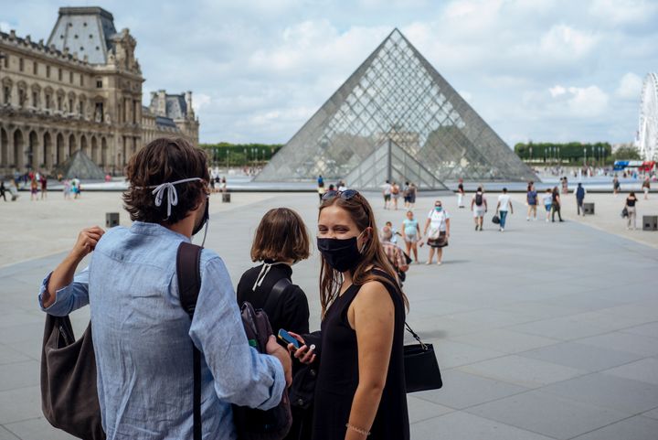Με μάσκες μπροστά στην πυραμίδα, στο Λούβρο, καθώς είιναι πλέον υποχρεωτικές για να κινείσαι στο Παρίσι. (AP Photo/Kamil Zihnioglu)