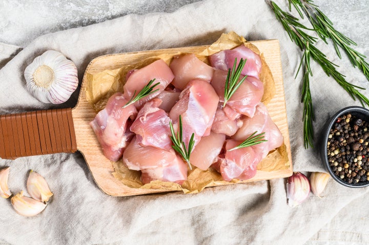 chicken thigh fillet cut into cubes. Gray background. Top view.