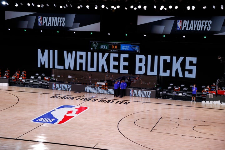 Referees huddle on an empty court during the Milwaukee Bucks and the Orlando Magic's scheduled game on Wednesday. The Bucks staged a walkout, prompting other teams to do the same. 