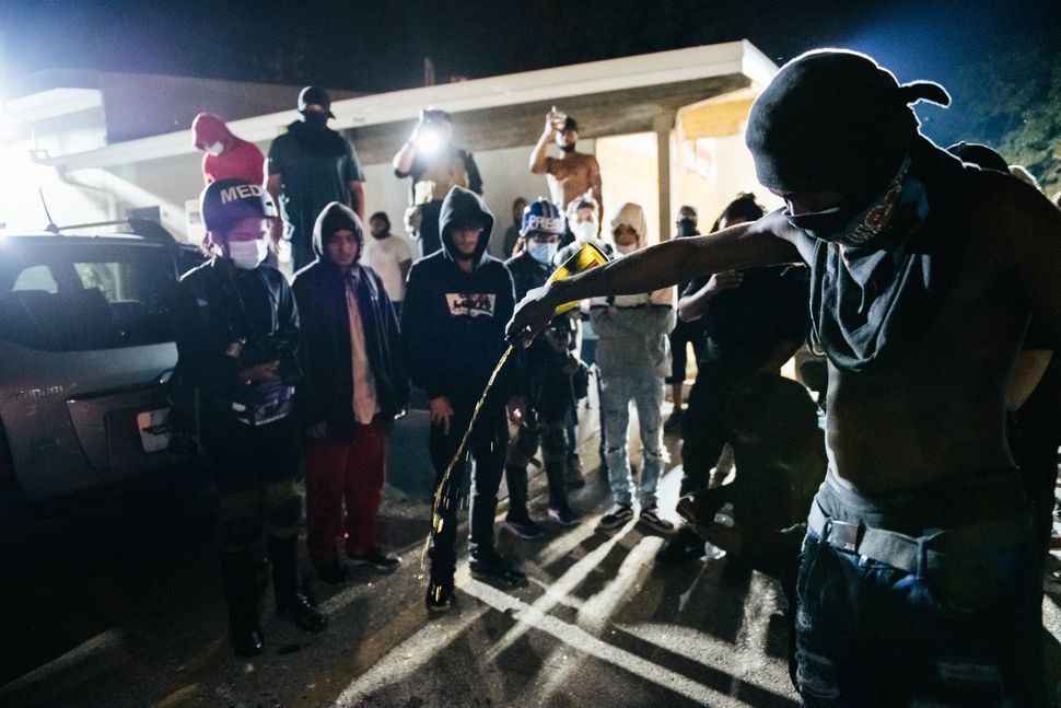 A man pours out an alcoholic beverage where an anti-racism protester was killed in Kenosha, Wisconsin, this week. 