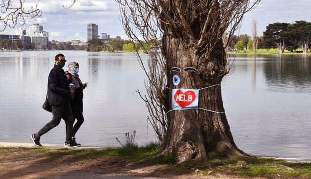 People wearing face masks exercise around the Albert Park Lake in Melbourne on August 26, 2020, as the city battles an outbreak of the COVID-19.