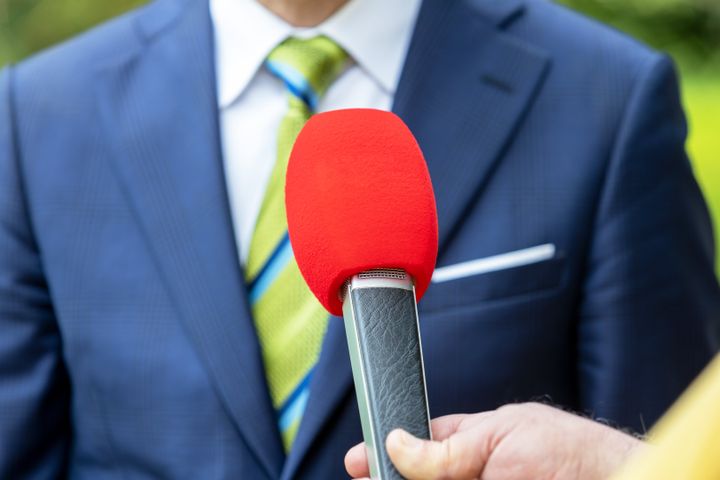 Reporter holding microphone making media interview with politician or business person