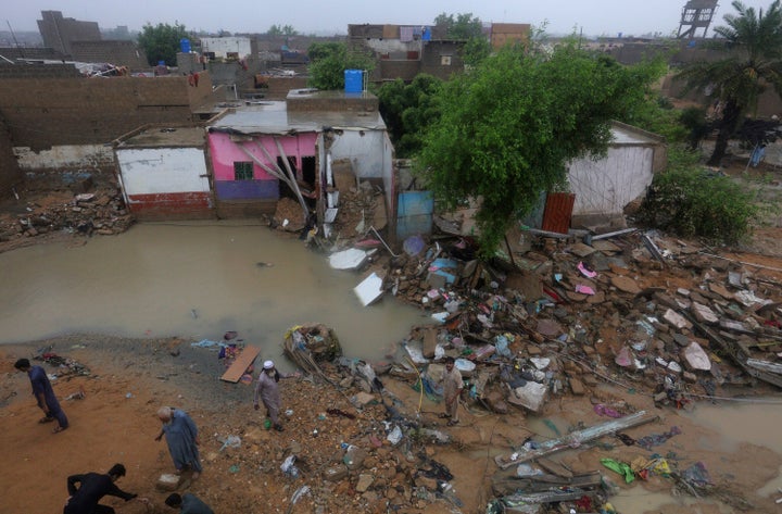 Local residents gather beside their damaged houses caused by heavy monsoon rains, in Yar Mohammad village near Karachi, Pakis