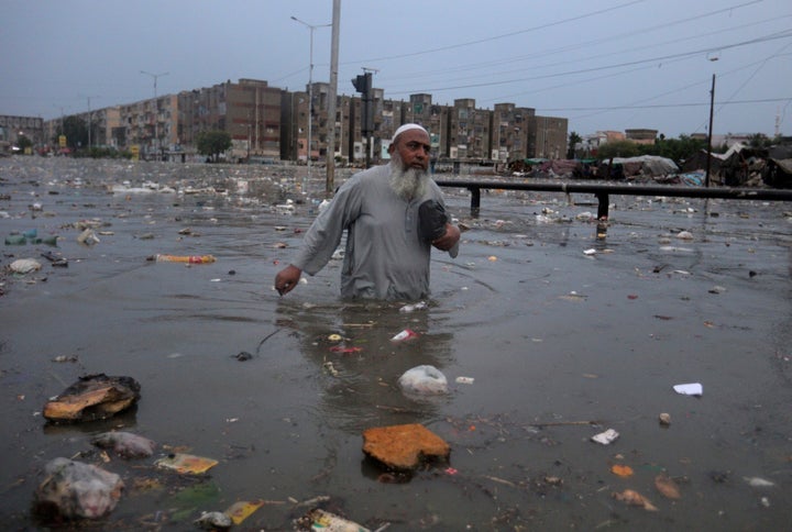 A man wades through a flooded road after a heavy rainfall in Karachi, Pakistan, Friday, Aug. 21, 2020.