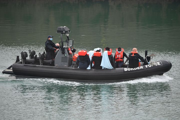 UK Border Force officials transfer migrants in a patrol vessel after they were intercepted while travelling in a RIB from France to Dover, at the Marina in Dover on August 14, 2020