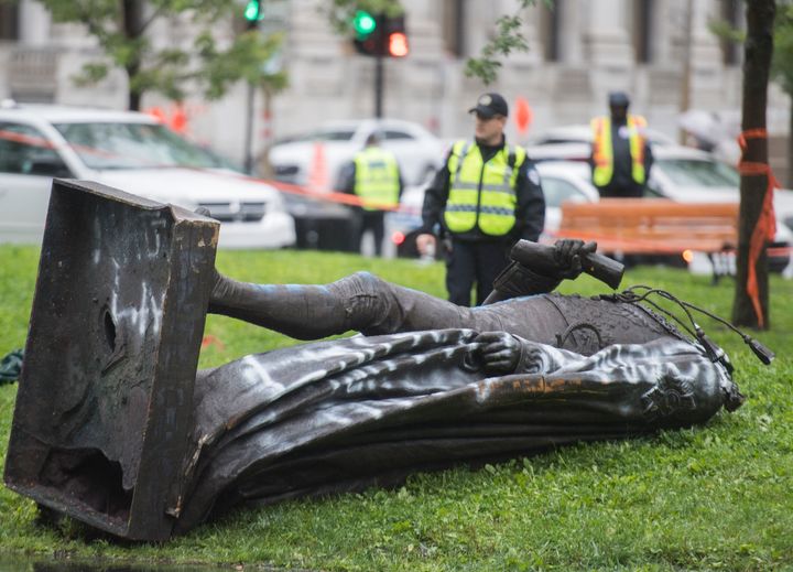 Police officers are shown next to a statue of Sir John A. MacDonald after it was torn down following a demonstration in Montreal on Aug. 29, 2020. 