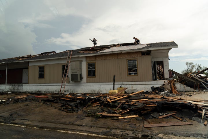 Men work on a damaged home in Lake Charles, Louisiana as the motorcade for President Donald Trump passes by.