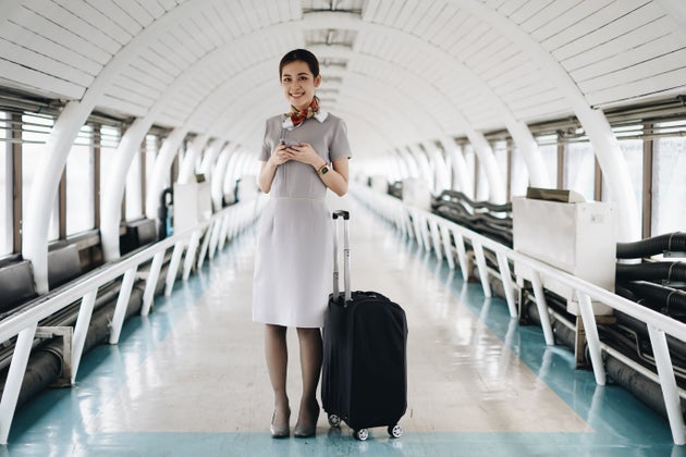 Portrait of beautiful hostess in airport with mobile phone.