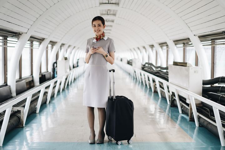 Portrait of beautiful hostess in airport with mobile phone.