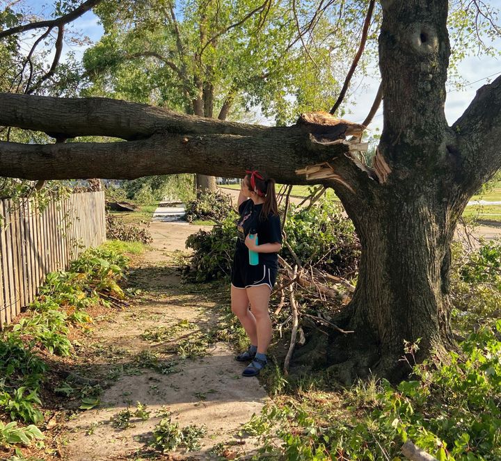 The writer stands by a tree in her Cedar Rapids, Iowa, neighborhood damaged by a Category 4 windstorm called a derecho in early August of this year.