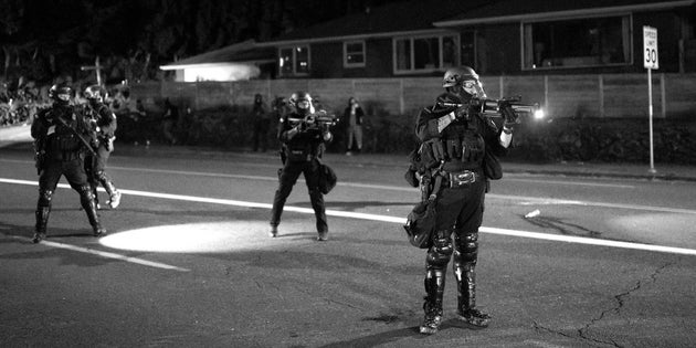 A Portland police officer points a less-lethal weapon at anti-police protesters a day after political...