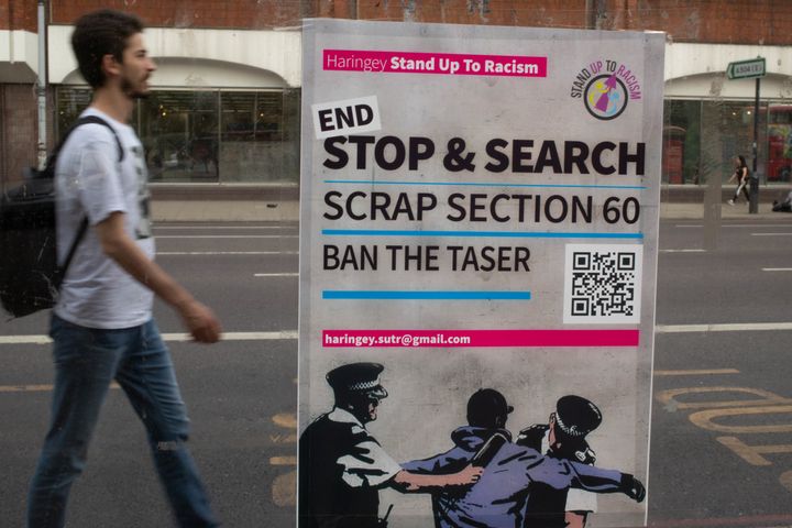 A man walks past a poster calling for an end to section 60 near Tottenham Police Station. 