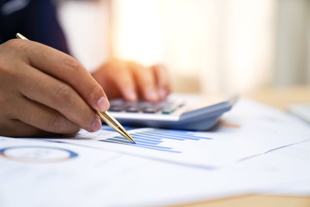 Businessman analyzing investment charts with calculator.