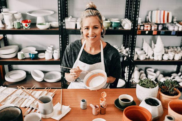 Woman sitting painting a pottery bowl in her workshop