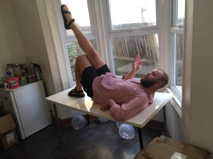 Sam models a kitchen table with his leg pointed in the air.