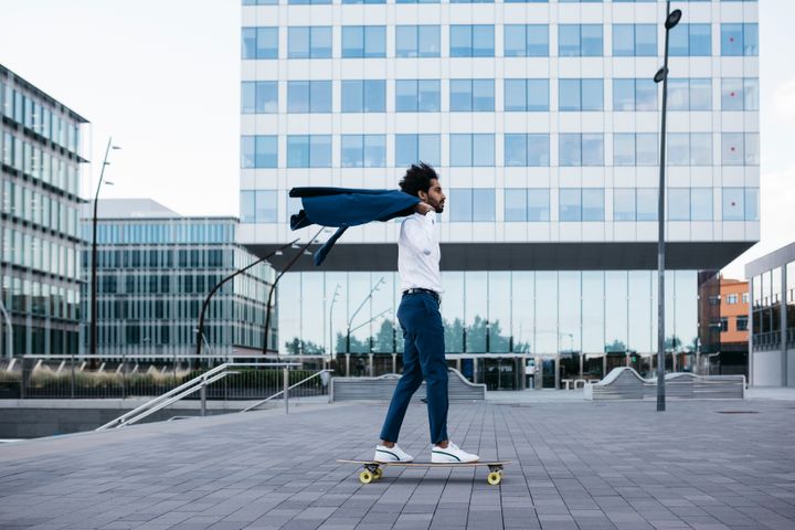 Young businessman riding a skateboard in the city