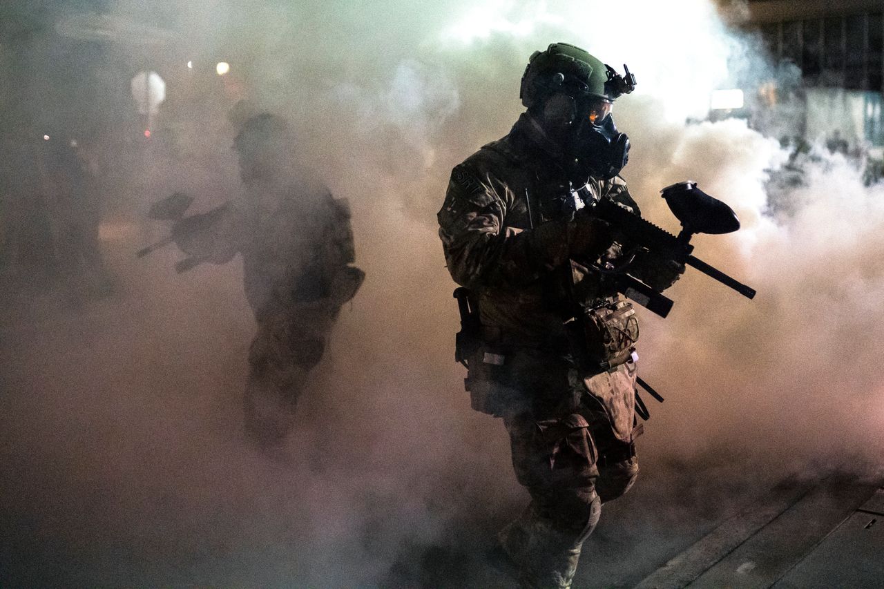 Federal officers walk through tear gas during a dispersal of about 300 protesters in front of the Immigration and Customs Enforcement detention building in Portland, Oregon.