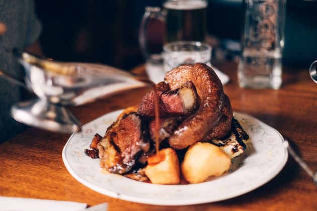 Traditional British Sunday roast dinner with beef, vegetables, gravy and a Yorkshire pudding.