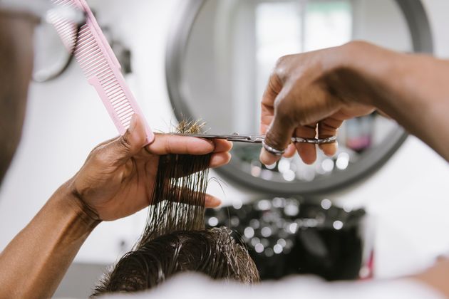 Close-up of barber cutting hair of a customer in barber shop