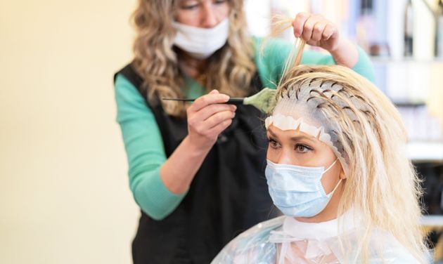 Hairdresser bleaching strands of hair with a rubber hat in beauty salon.